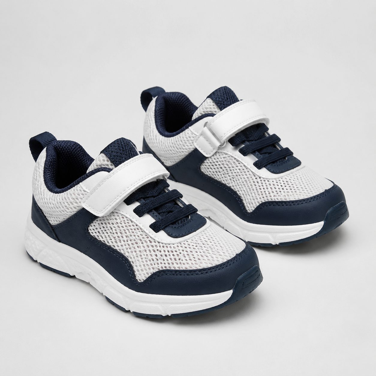 Pair of kids' sneakers with breathable mesh upper in a white and navy colorway